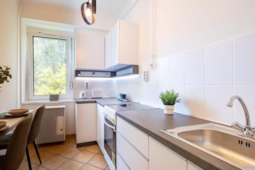 - une cuisine avec des placards blancs, un évier et une table dans l'établissement Cozy Home - Close to River - Easy Parking, à Budapest