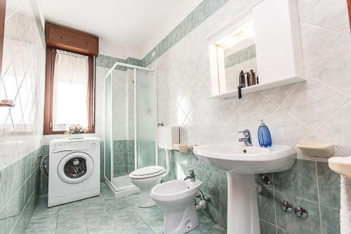 a bathroom with a sink toilet and a washing machine at Seaside happiness flat and shared pool in Rosolina in Rosolina Mare