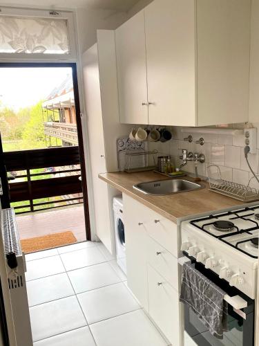 a white kitchen with a sink and a stove at Napsugár Retro Apartman in Gárdony