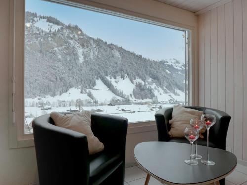a room with two chairs and a table with wine glasses at Holiday Home Chalet Guldeli by Interhome in Kandergrund