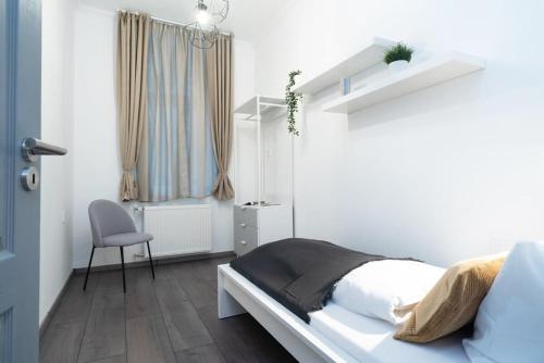 een witte slaapkamer met een bed en een stoel bij Ideal new apartment in the center in Boedapest