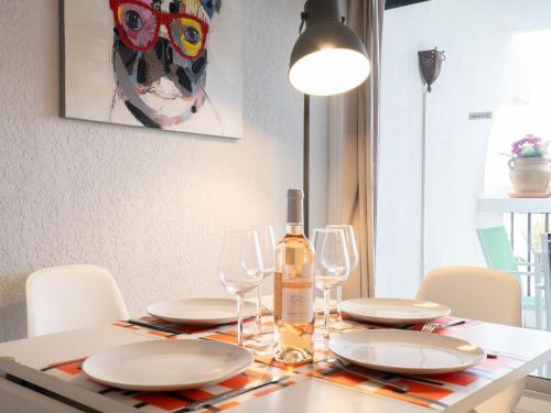 a dining room table with a bottle of wine on it at Studio Ulysse Plage-5 by Interhome in La Grande Motte
