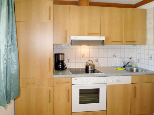 eine Küche mit Holzschränken und einem weißen Herd mit Backofen in der Unterkunft Apartment Kammerlander - NKI135 by Interhome in Neukirchen am Großvenediger