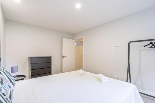 a white bedroom with a bed and a mirror at JMF House in São Vicente