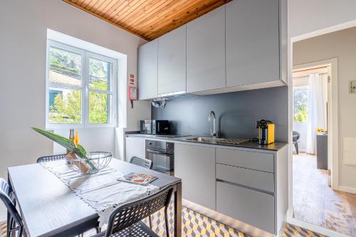 a kitchen with white cabinets and a table with chairs at JMF House in São Vicente