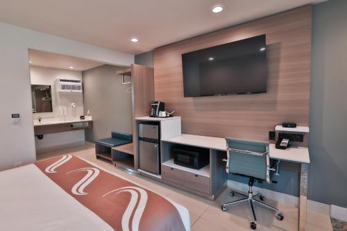 a hotel room with a desk and a tv on a wall at Hotel Miramar in San Clemente