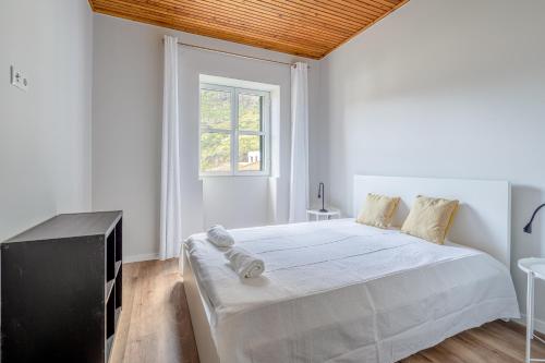 a white bedroom with a large bed and a window at JMF House in São Vicente