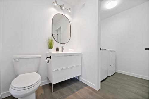 a white bathroom with a toilet and a mirror at Maison Oasis by Rendez-Vous Mont-Tremblant in Saint-Faustin