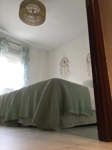 a green blanket on a bed in a room at Alojamiento Seda in Alcalá de Guadaira