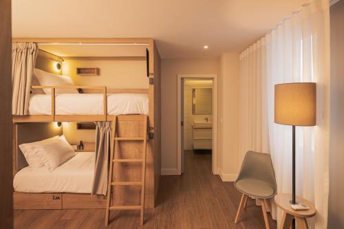 a room with bunk beds with a desk and a chair at Monturi Hostel in Ponta Delgada