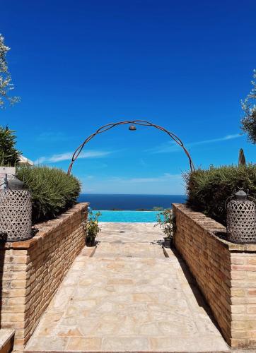 an arch over a walkway with the ocean in the background at Pamperduto Country Resort in Porto Potenza Picena