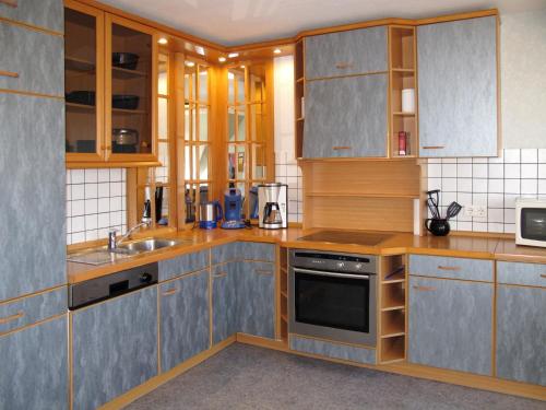 una cocina con armarios de madera y electrodomésticos de acero inoxidable en Apartment Hof Bajema by Interhome en Oberndorf