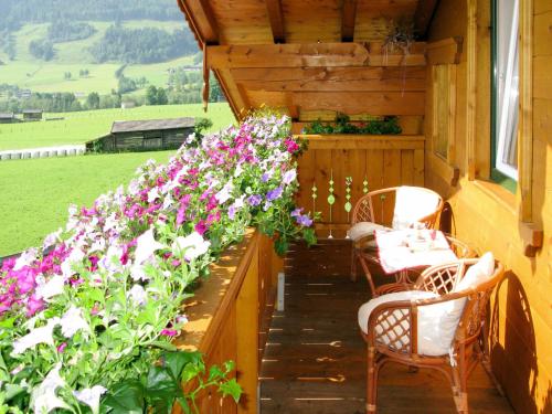eine Veranda mit Stühlen und Blumen auf einem Haus in der Unterkunft Apartment Gruber by Interhome in Leogang