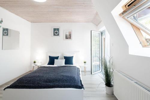 um quarto branco com uma cama grande e almofadas azuis em Teljesen felújított, szépen berendezett nyaraló em Balatonfenyves