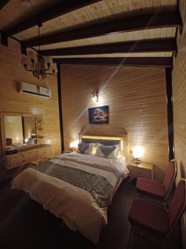 1 dormitorio con 1 cama grande y 1 silla en اكواخ الماريا en Arar