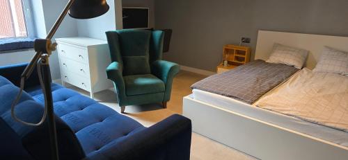 a bedroom with a bed and a chair next to a bed at Apartamenty STARA PIEKARNIA in Płock