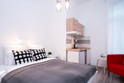 een slaapkamer met een bed en een rode stoel bij New comfy studio at convenient location in Boedapest
