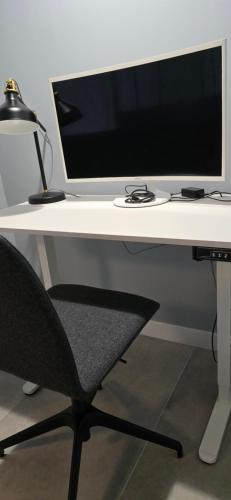 a white desk with a computer monitor and a chair at Apartamenty STARA PIEKARNIA in Płock