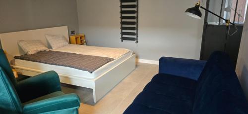 a bedroom with a bed and two chairs and a couch at Apartamenty STARA PIEKARNIA in Płock