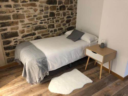 uma cama num quarto com uma parede de tijolos em Casa Toronzue em Frajén