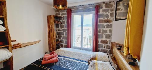 a bedroom with a stone wall and a window at Magnifique appartement avec balcon vue mer à l'entrée d'Ajaccio in Ajaccio