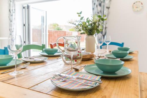 a wooden table with plates and bowls and glasses at Kingsmead - Bracklesham Bay in Chichester