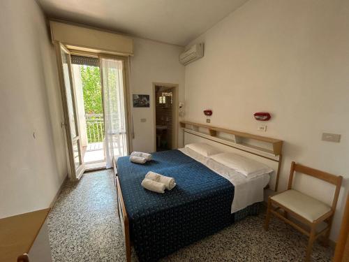 a bedroom with a bed and a chair and a window at Camere Capinera in Cesenatico
