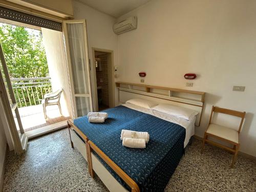 a bedroom with a bed with two towels on it at Camere Capinera in Cesenatico