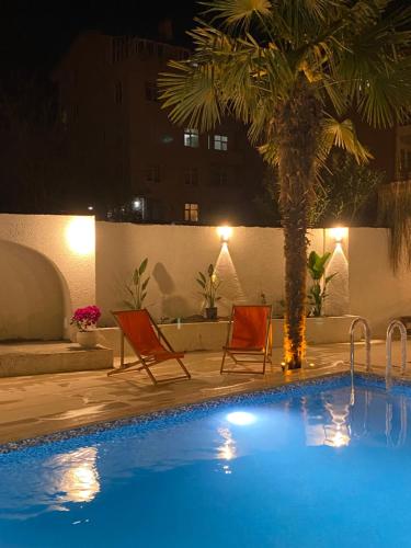 a pool with two chairs and a palm tree at night at EVİM APART HOTEL in Termal
