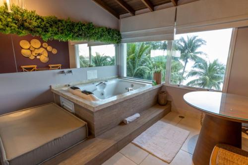 a large bathroom with a tub and a table at Amora Hotel Maresias in Maresias