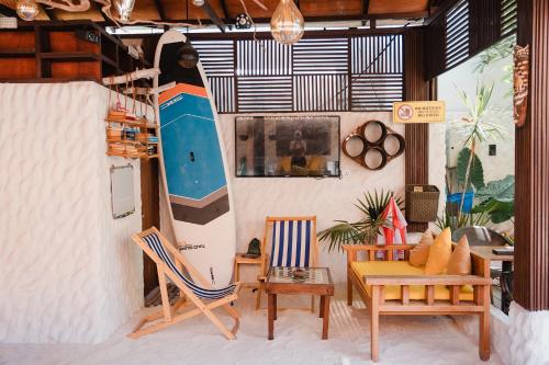 a surfboard hanging on a wall in a room with chairs at Atholhu Residence in Fehendhoo