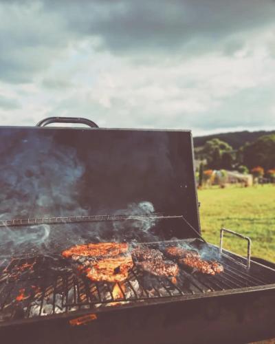a grill with a bunch of food cooking on it at Greenacres Glamping in Lea