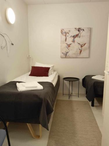 Zimmer mit 2 Betten, einem Tisch und einem Gemälde in der Unterkunft Einonhovi in Ylivieska