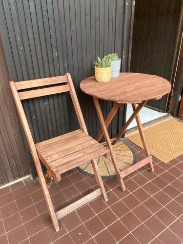 a wooden table and a chair next to a table and a plant at Napsugár Retro Apartman in Gárdony
