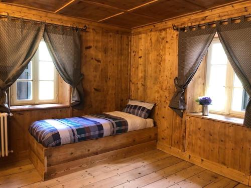 a bedroom with a bed in a cabin with windows at Rifugio Teggiate in Madesimo