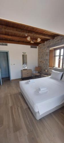 a large white bed in a room with wooden floors at Koukouri Suites in Areopolis