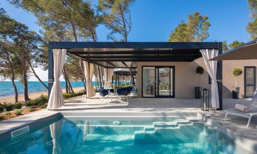 a swimming pool in front of a house at Aminess Avalona Glamping Villas & Mobile Homes in Povljana