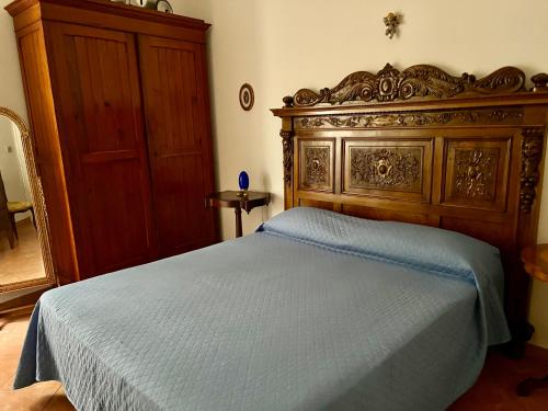 een slaapkamer met een groot bed met een houten hoofdeinde bij Casa del Duomo in Siracusa