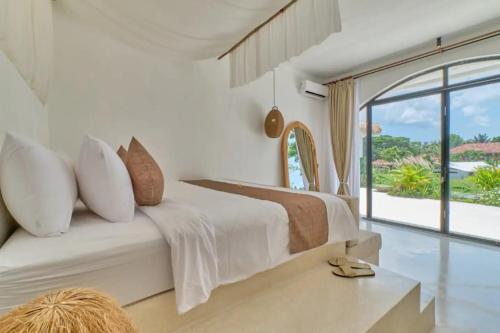 um quarto branco com uma cama grande e uma janela grande em Romantic Serenity Villa in Ubud em Ubud