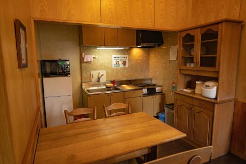 a small kitchen with a table and a refrigerator at Morinoyu Hotel Hanakagura in Asahikawa