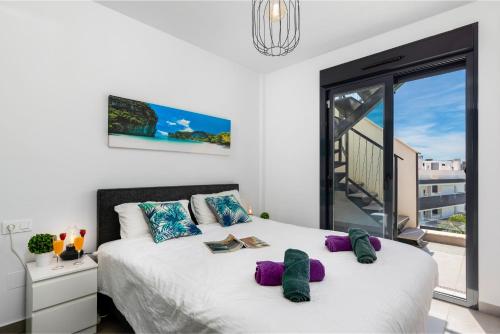 een slaapkamer met een groot wit bed met paarse kussens bij Baliante - penthouse, 2 bedrooms, 2 pools, jacuzzi, Orihuela Costa in Orihuela