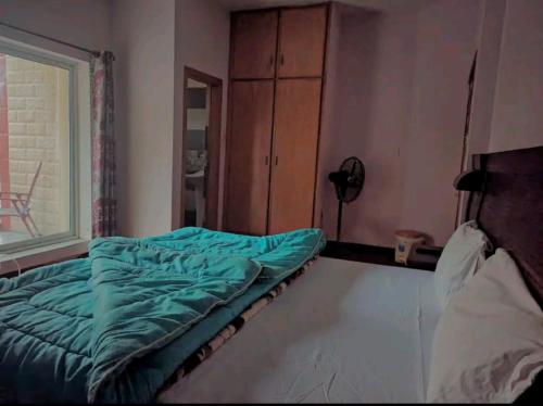 a bed sitting in a room with a window at Al Sadiq Guest House in Murree