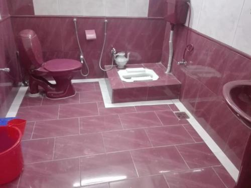 a red bathroom with a toilet and a sink at Al Sadiq Guest House in Murree