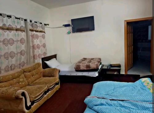 a living room with a couch and a tv at Al Sadiq Guest House in Murree