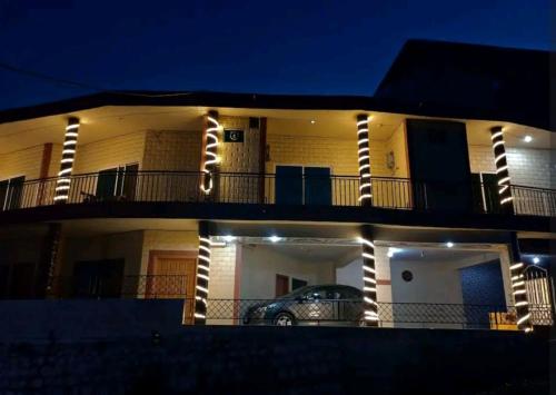 a building with a car parked in front of it at night at Al Sadiq Guest House in Murree