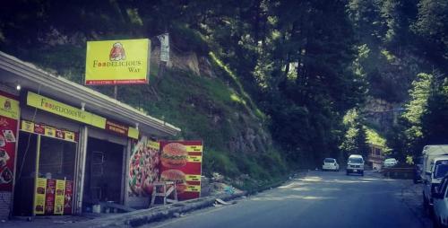 two cars driving down a road next to a mountain at Al Sadiq Guest House in Murree