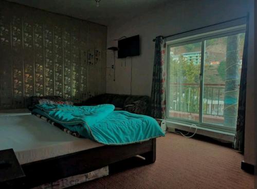 a bedroom with a bed and a large window at Al Sadiq Guest House in Murree