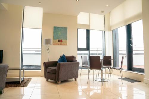 a living room with chairs and a table and windows at The Western Citypoint Apartments in Galway