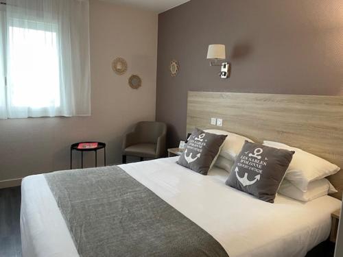 sypialnia z dużym łóżkiem i krzesłem w obiekcie Cit'Hotel Le Chêne Vert w mieście Les Sables-dʼOlonne
