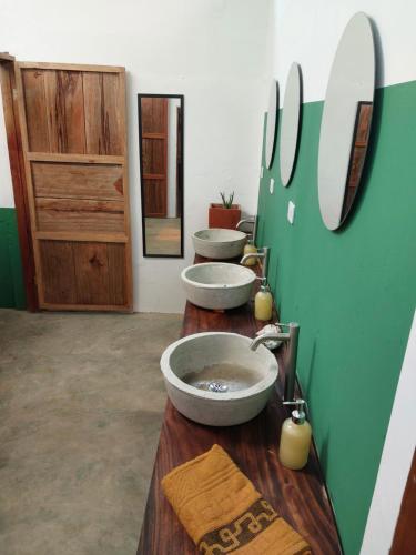 a bathroom with three sinks on a wooden counter at Hostel Nugeku in Rincón
